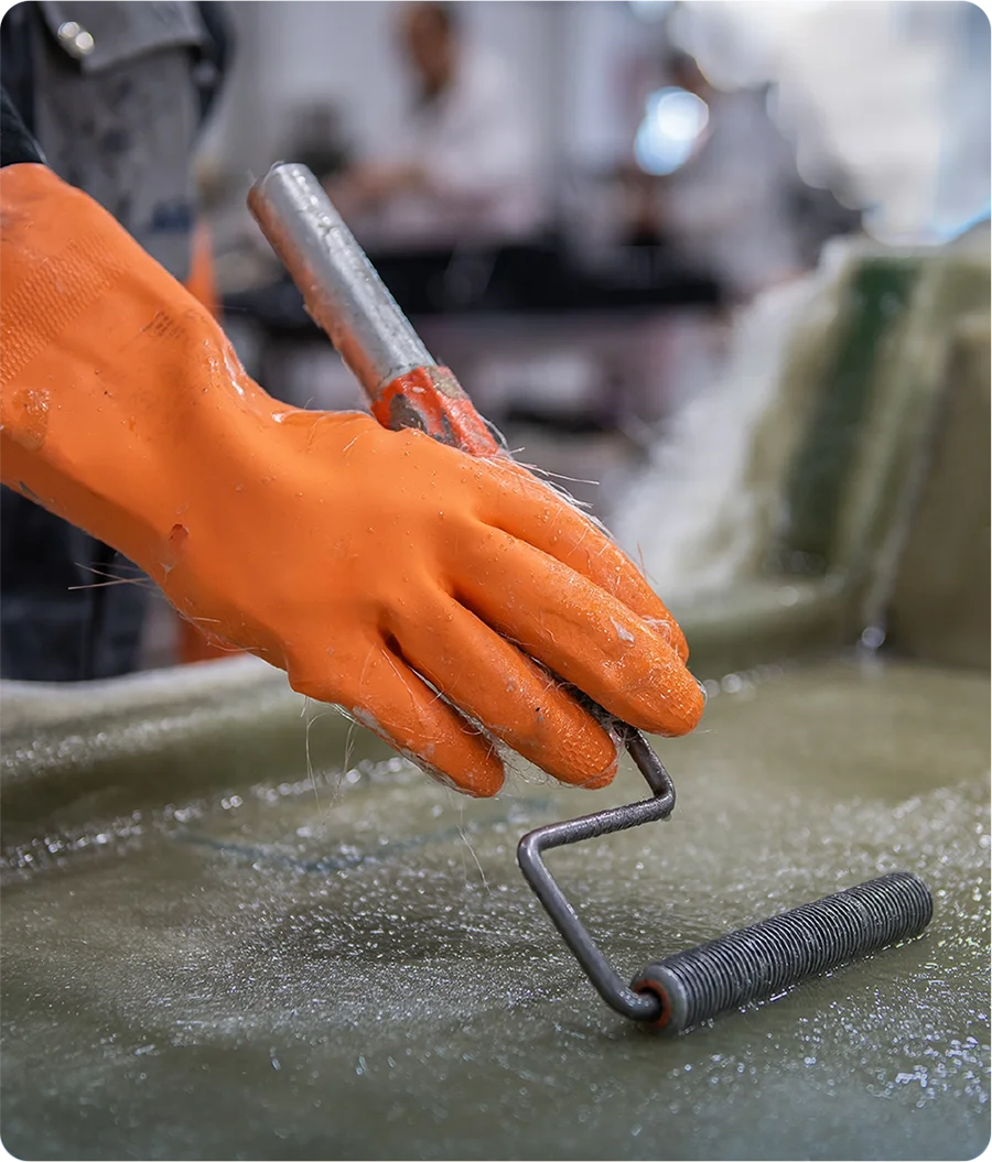Fiberglass application with a roller on a pool mold at the Fiber factory