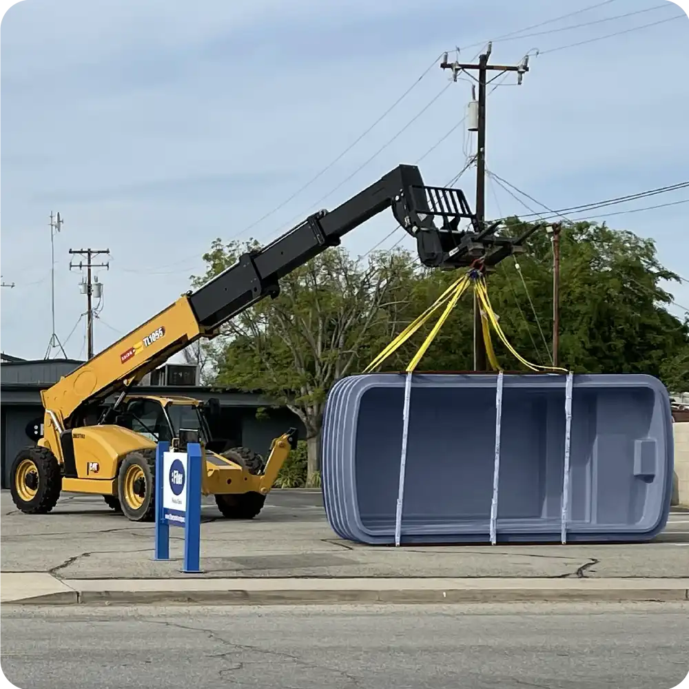 Crane equipment handling and positioning fiberglass pool on project jobsite