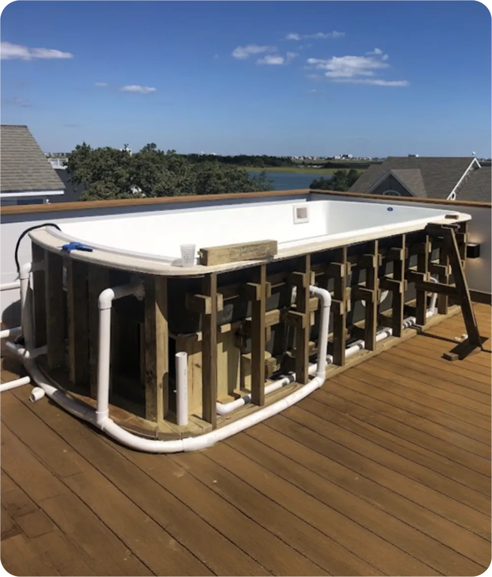 Prefabricated fiberglass pool structure installation on townhome wooden deck