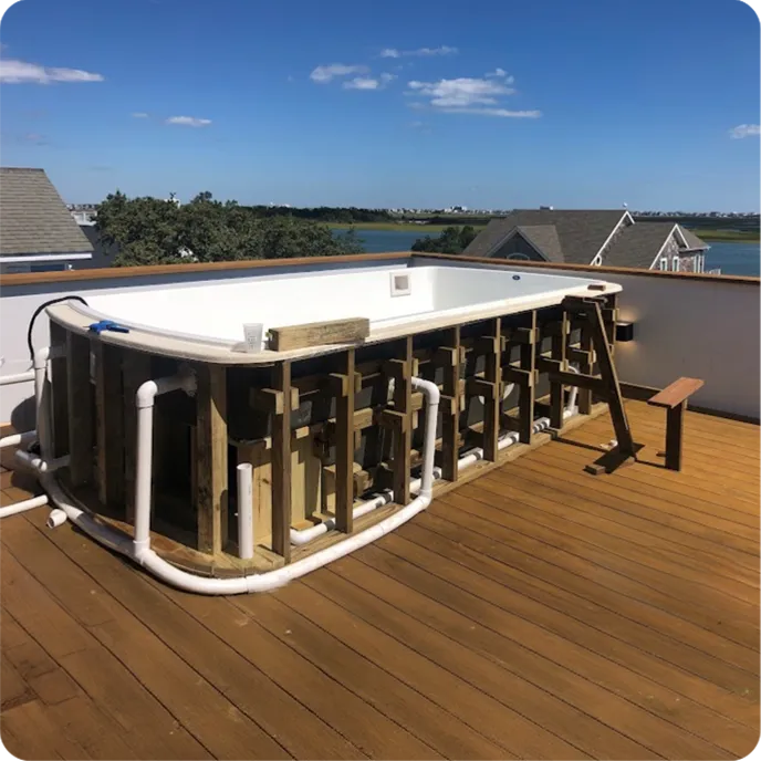 Prefabricated fiberglass pool structure installation on townhome wooden deck