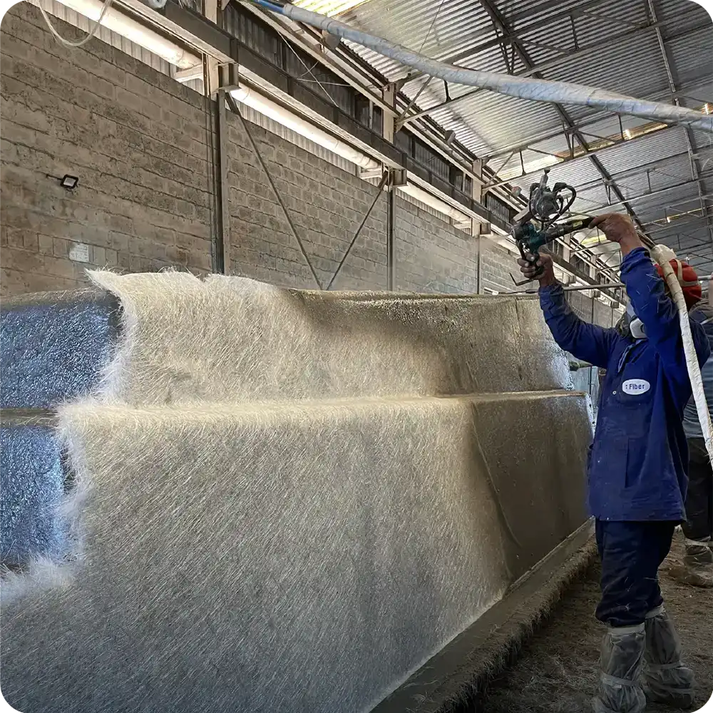 Worker applying fiberglass laminate to a pool mold in Fiber manufacturing facility