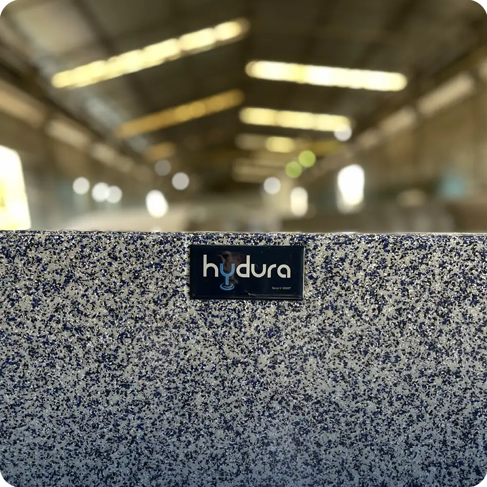 Speckled Hydura private label pool surface with factory production in the background